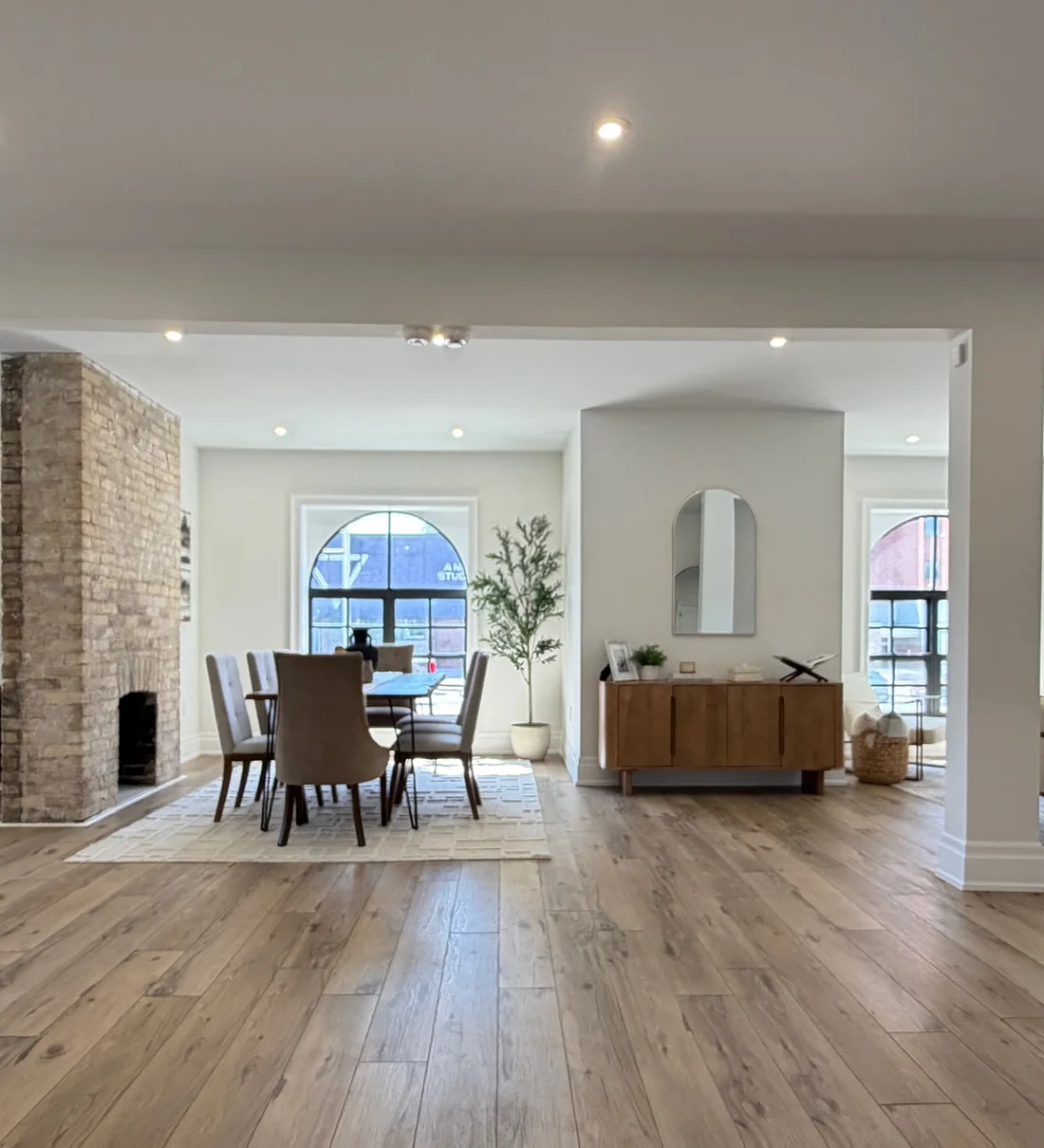 The open main floor of The Beacon with twin arched windows, brick fireplace and natural light